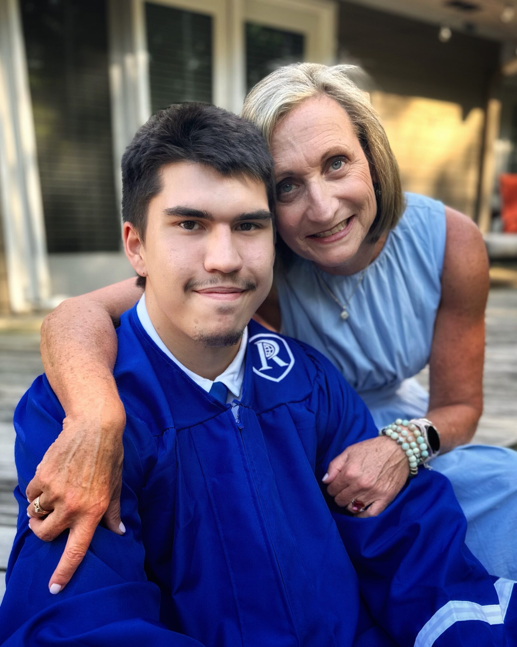 Young graduate with woman embracing him, smiling.