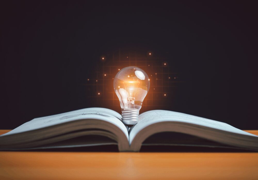 Open book with glowing light bulb.