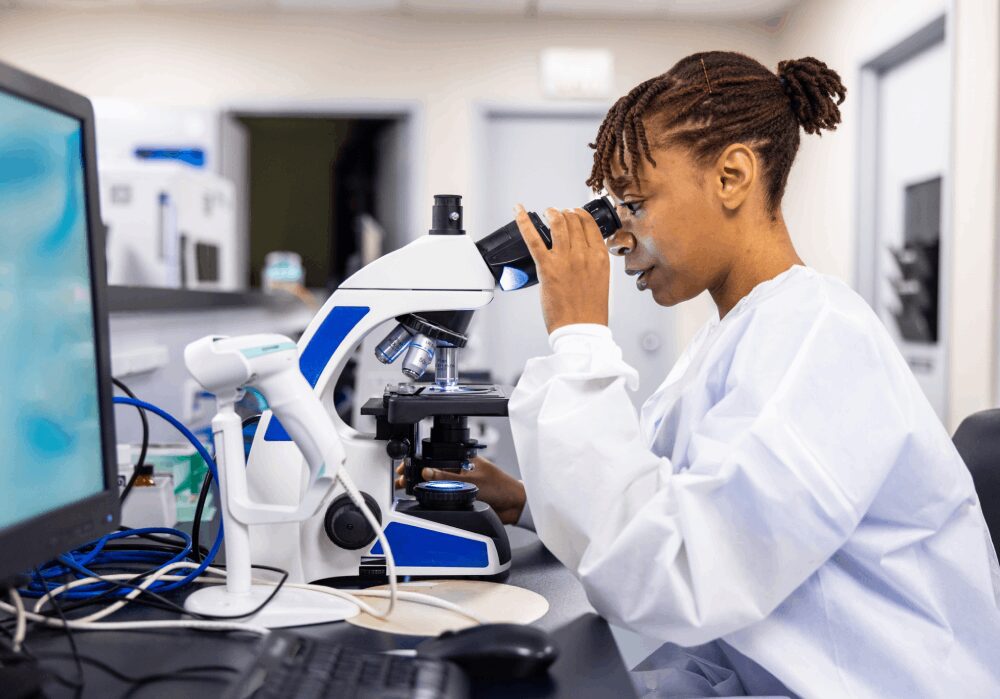 Scientist examining sample under a microscope.