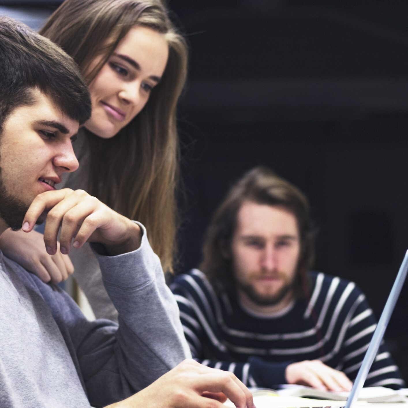 Three people collaborating on a laptop.